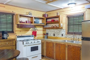 A compact kitchen with wooden cabinets, a stove, and a refrigerator.