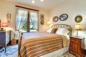 Ein Schlafzimmer mit einem Bett, Nachttischlampen, einem Schminktisch und einem Fenster mit Vorhängen.