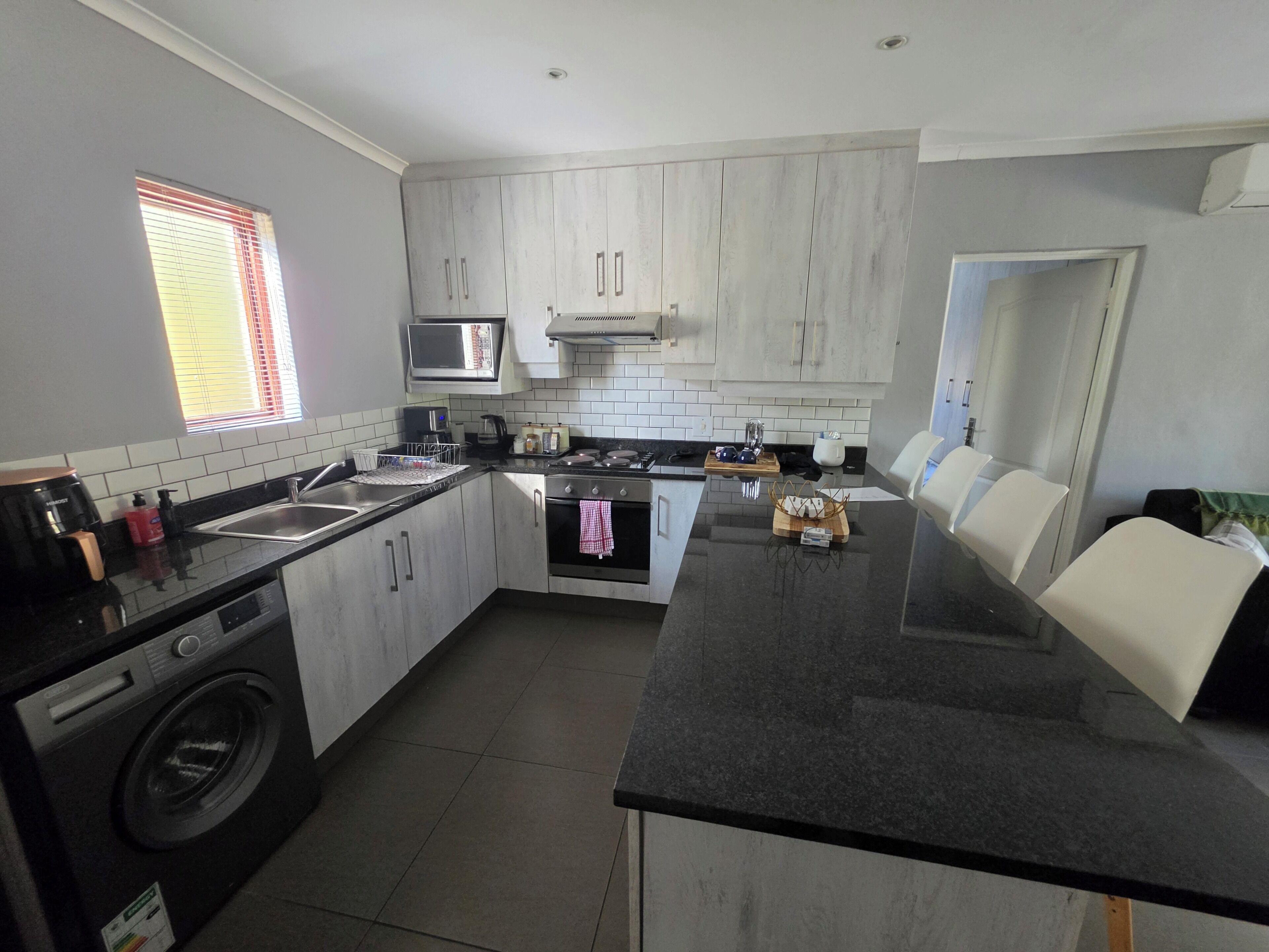 A modern kitchen with a central island, built-in appliances, and a washing machine.