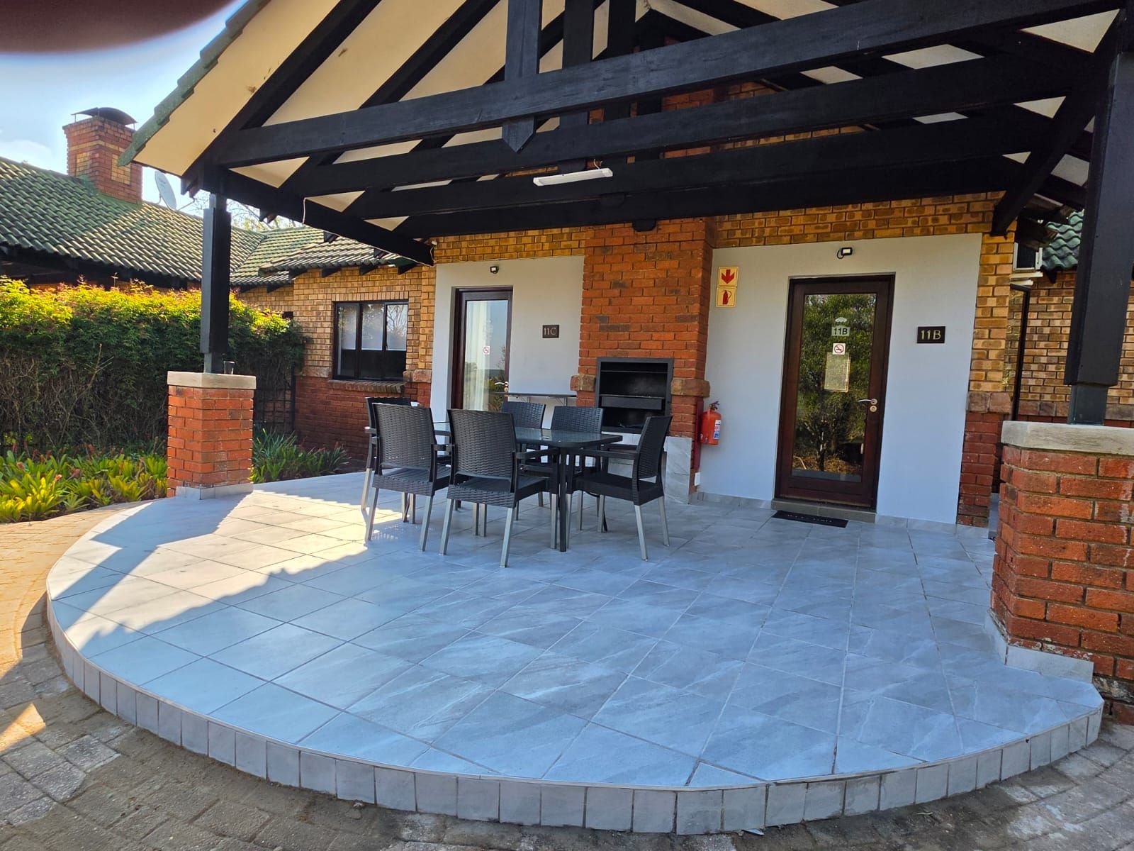 A covered patio with a brick wall, a door, and a table with chairs.