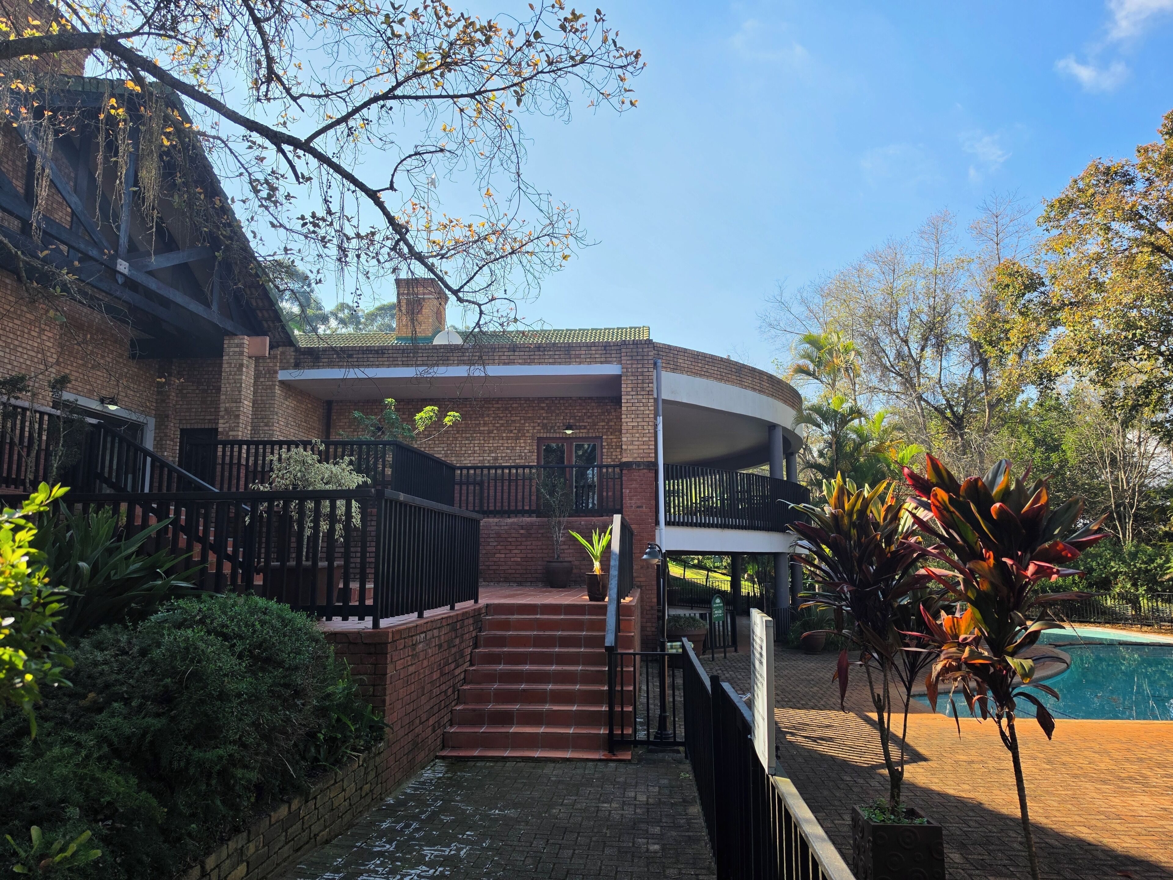 A two-story house with a brick exterior, a front porch, and a pool.