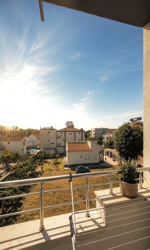 A balcony with a view of a residential area, including houses and a swimming pool. - Guest House Fjola : One-Bedroom Apartment (Donji Štoj)