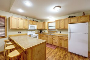 A kitchen with wooden cabinets, a white stove, a microwave, a refrigerator, and a window with blinds. - Great for Families! Wolf pen Gap ATV Base on Creek (Mena)