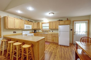 A kitchen with wooden cabinets, a central island with stools, a refrigerator, and a dining table with chairs. - Great for Families! Wolf pen Gap ATV Base on Creek (Mena)