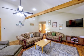 A living room with two sofas, a coffee table, a television, and a ceiling fan. - Great for Families! Wolf pen Gap ATV Base on Creek (Mena)