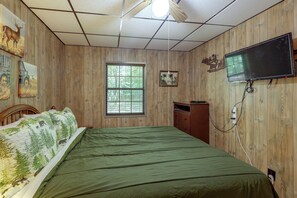 Una camera da letto con un letto, una finestra, una televisione e pareti in legno.