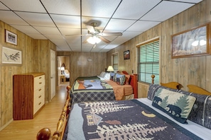 A room with two beds, wooden walls, a ceiling fan, and framed pictures. - Wolf Pen Gap ATV Secluded Family Sanctuary (Mena)