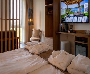 A hotel room with a bed, a chair, a TV, and a minibar. - Lake View Hotel Room 2p in Thorn (Thorn)