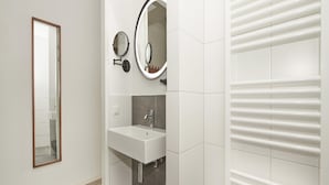 Ein Badezimmer mit einem weißen Waschbecken, zwei Spiegeln und einem Handtuchhalter.