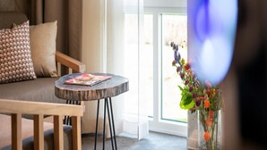 Ein Zimmer mit einer Couch, einem kleinen runden Tisch und einer Vase mit Blumen.