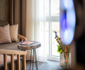 A room with a sofa, a small round table, and a vase with flowers. - Lake View Hotel Room 2p in Thorn (Thorn)