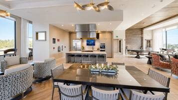 A modern kitchen with a central island, bar stools, and a dining area with a large table and chairs.