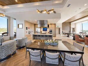 A modern kitchen with a central island, bar stools, and a dining area with a large table and chairs. - Luxury North Retreat with Pool and Gym (Naples)
