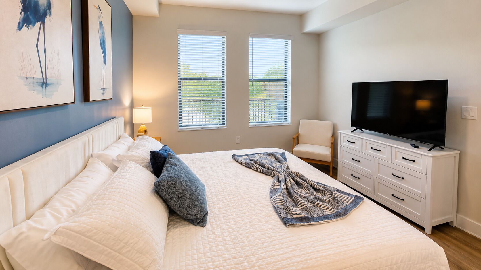 Una camera da letto con un letto, una televisione, una sedia e due finestre con tende.
