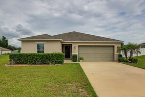 A single-story house with a garage, a front lawn, and a well-maintained hedge. - Gateway to Disney! Home w/ Fenced Yard & Office (Mascotte)