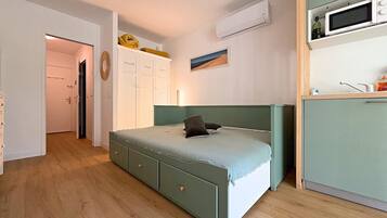 Ein Schlafzimmer mit einem Bett, einem Kleiderschrank, einem Schreibtisch und einer Mikrowelle.