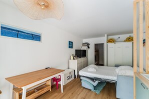 Ein gemütlicher Raum mit einem Bett, einem Schreibtisch, einem Stuhl, einem Fernseher und einem Kleiderschrank.
