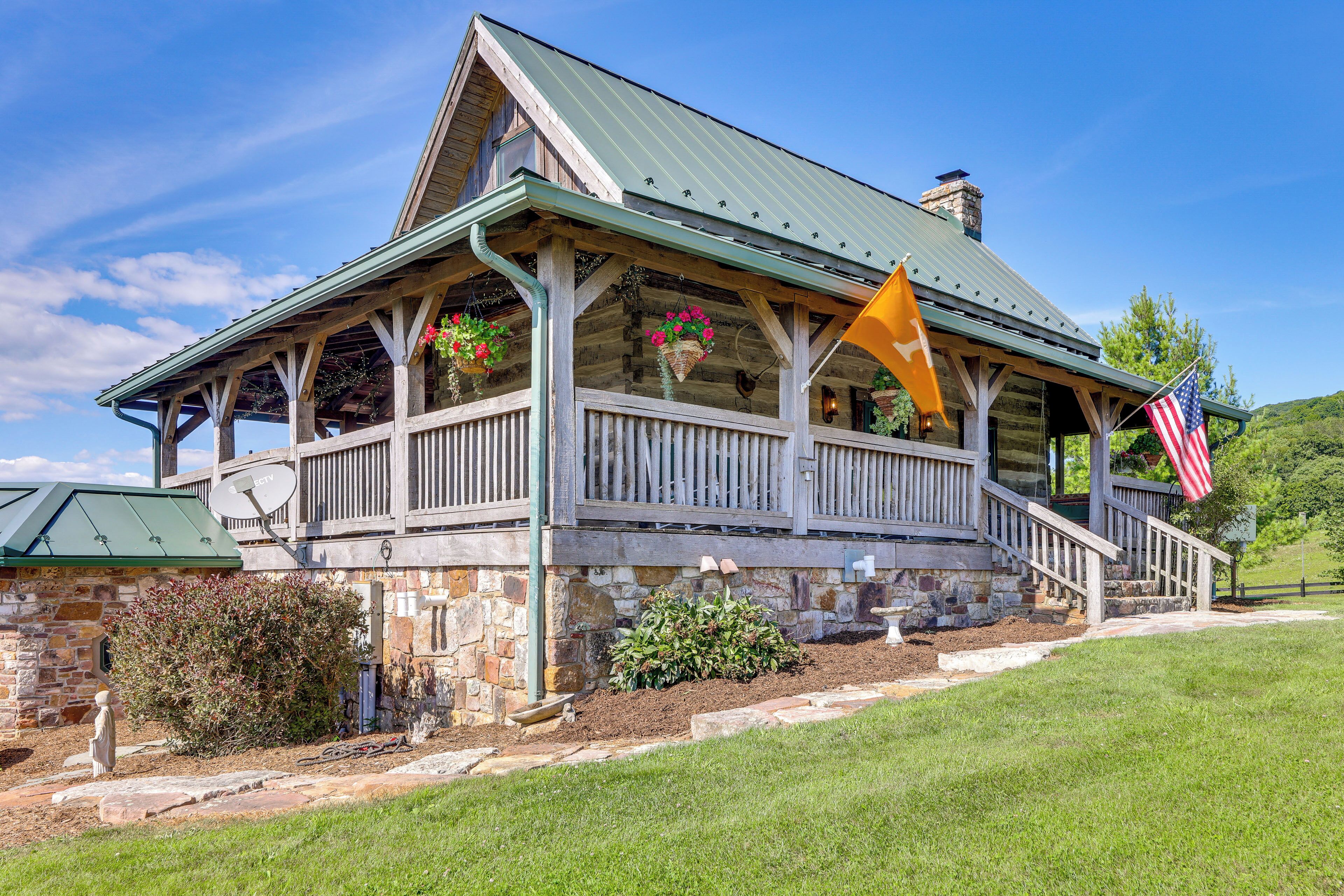 A stone building with a porch, a flag, and a satellite dish.