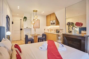 Ein Hotelzimmer mit Bett, Schreibtisch, Stuhl, Küchenzeile und Kamin.