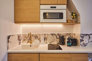 Eine moderne Küche mit Marmor-Spritzschutz, Holzschränken, einem eingebauten Backofen und einer Kaffeemaschine.