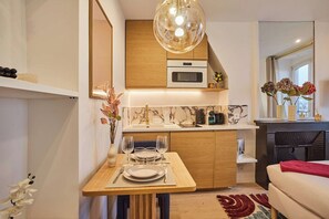 Eine moderne Küche mit einer Holz Arbeitsplatte, einem eingebauten Ofen und einem Essbereich mit Tisch für zwei Personen.