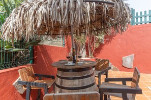 Una mesa de barril de madera con sillas, una botella de vino y una copa de vino tinto.
