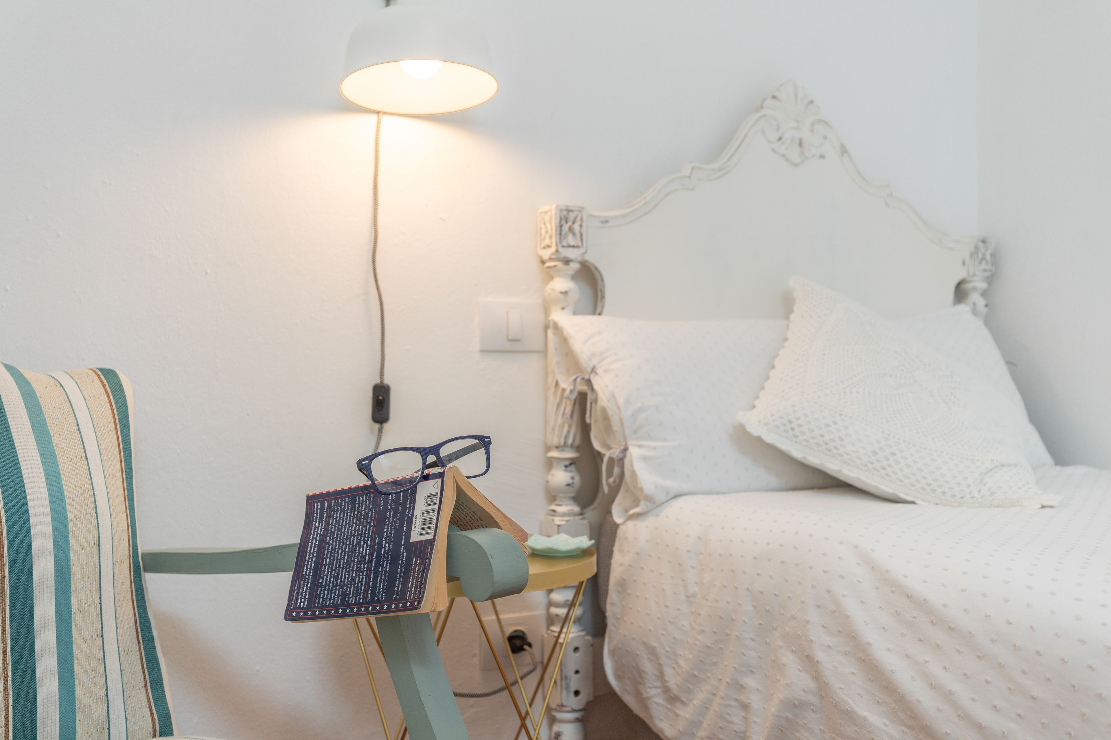 Un dormitorio con una cama, una mesita de noche, una lámpara y una silla.