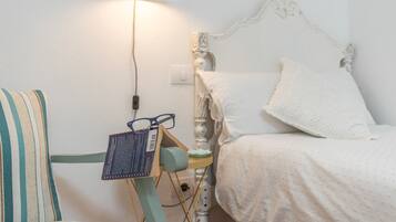 Un dormitorio con una cama, una mesita de noche, una lámpara y una silla.