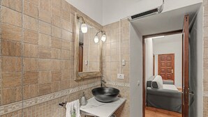 Ein Badezimmer mit einem großen Spiegel, einem schwarzen Waschbecken und einem Handtuchhalter.