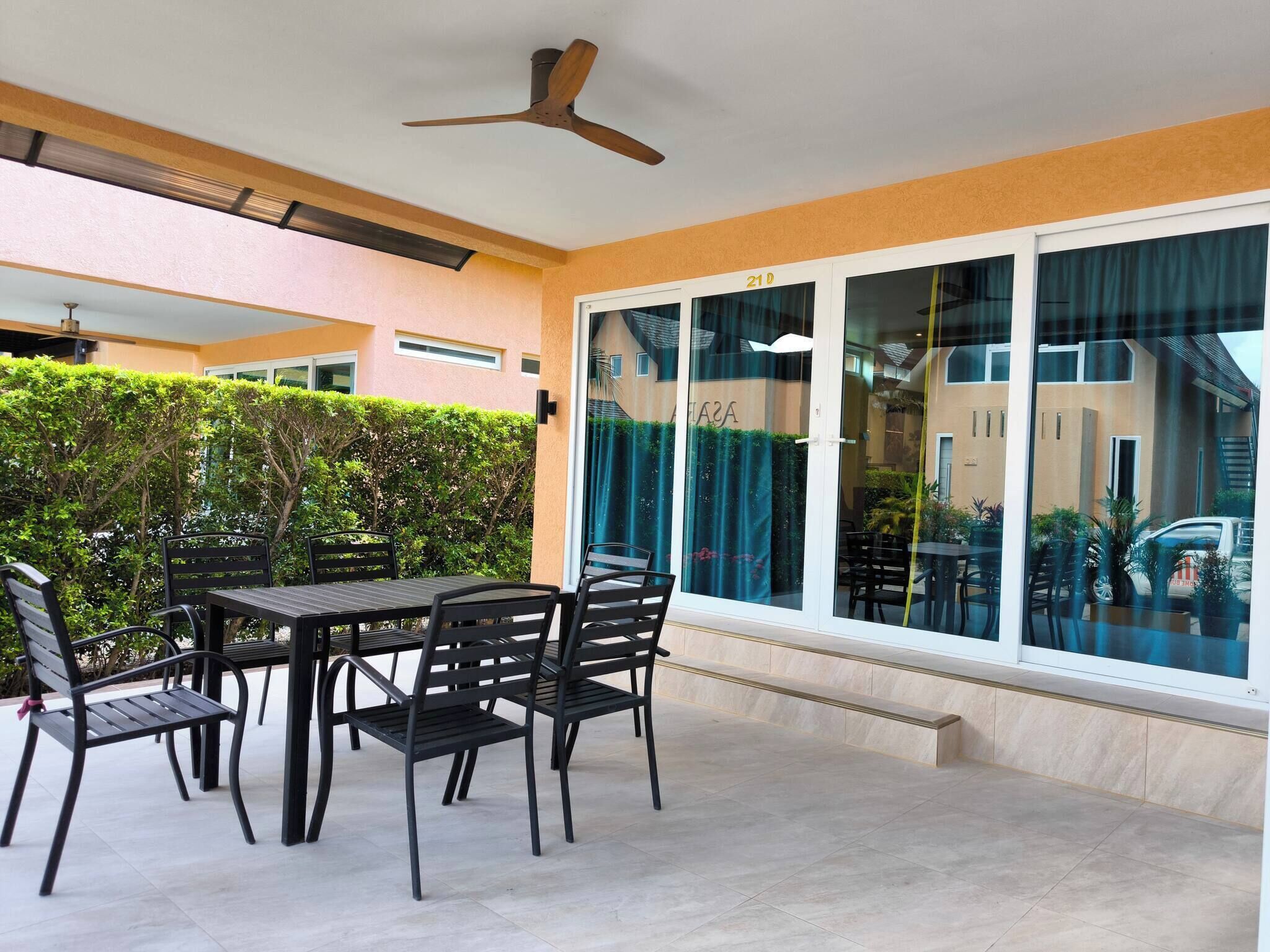 A patio with a table and chairs, a ceiling fan, and a large window with a view of the street.