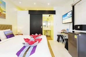 Ein Hotelzimmer mit Bett, Schreibtisch, Fernseher und Kühlschrank.