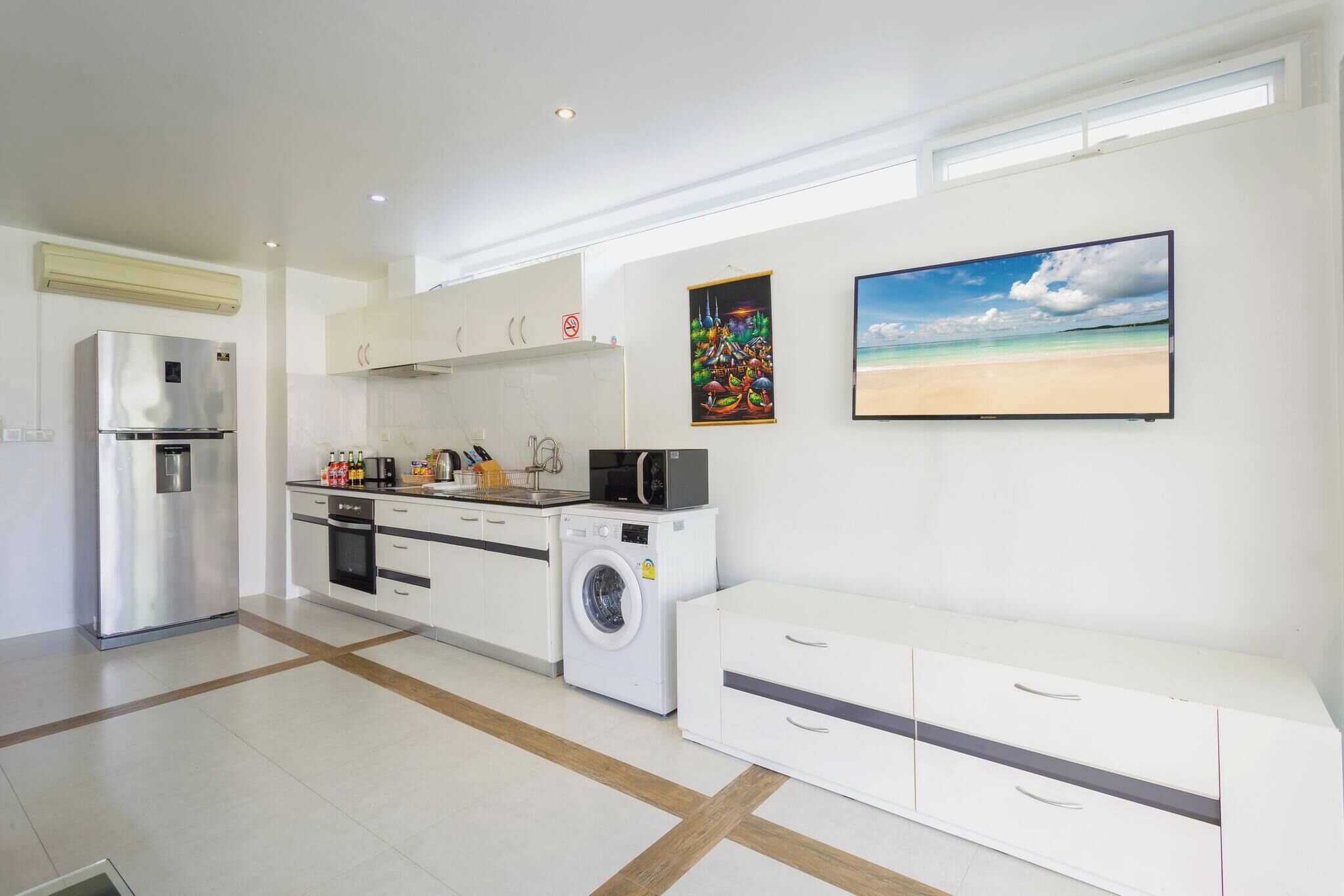 A modern kitchen with a built-in washing machine, a refrigerator, and a microwave.