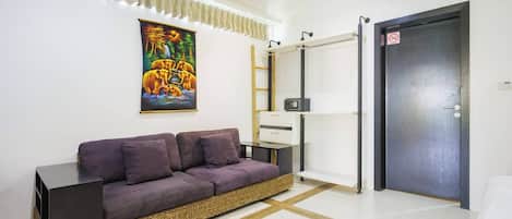 A modern living room with a sofa, a painting, a ladder, a desk, and a door.
