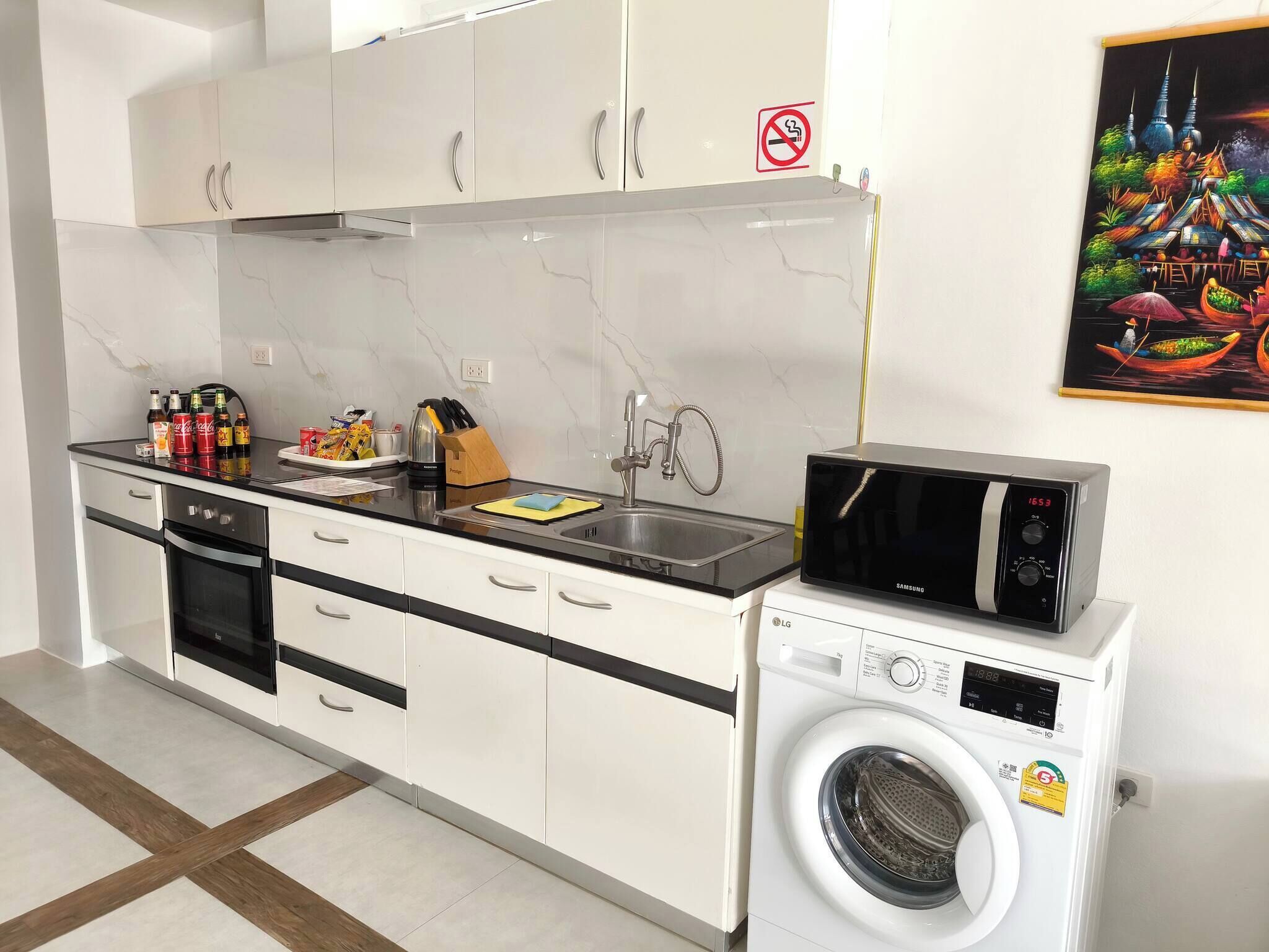 Una cucina moderna con forno a microonde, lavatrice e lavello.