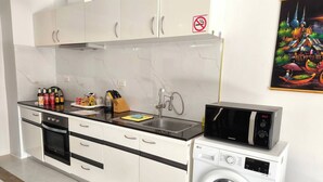 A modern kitchen with a microwave, washing machine, and a sink. - Beach Villa 21D Blue Haven Bay Resort - 4 Rooms (Ko Chang)