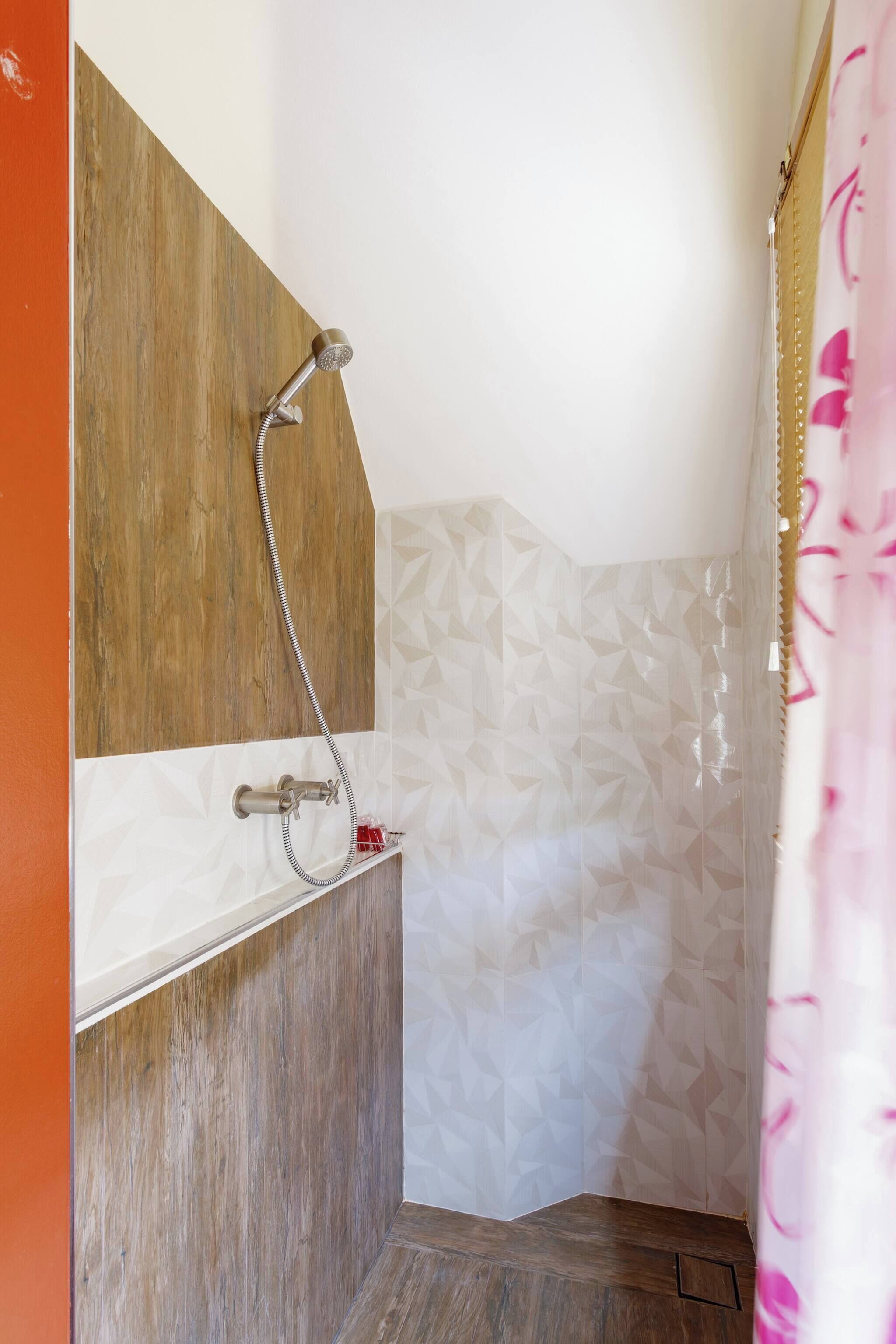 A shower area with a wooden panel wall, a showerhead, and a shower control.