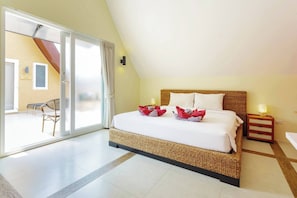A hotel room with a bed, a nightstand, a lamp, and a view of the outside.
