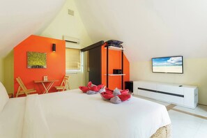 A hotel room with a bed, a TV, a window with blinds, a small table with a chair, and a painting on the wall. - Beach Villa 21D Blue Haven Bay Resort - 4 Rooms (Ko Chang)