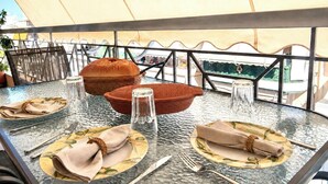 Une table dressée pour deux personnes, avec un plateau en verre, deux assiettes, des couverts et un bol.