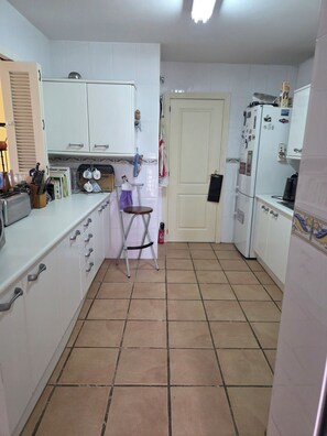A compact kitchen with white cabinets, a small dining table, and a tiled floor. - A lovely spacious 2-bed apartment  on beautiful El Presidente Urbanisation, (Estepona)