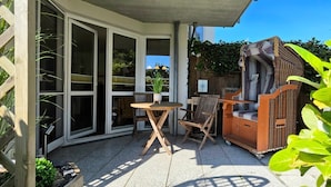 Un espace patio aménagé avec une table et des chaises, un canapé en osier et un meuble en bois.