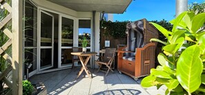 A patio area with a table and chairs, a wicker sofa, and a wooden cabinet. - Vacation Rental i38 - Ground-floor 2-room apartment near the beach, Wi-Fi (Graal-Müritz)