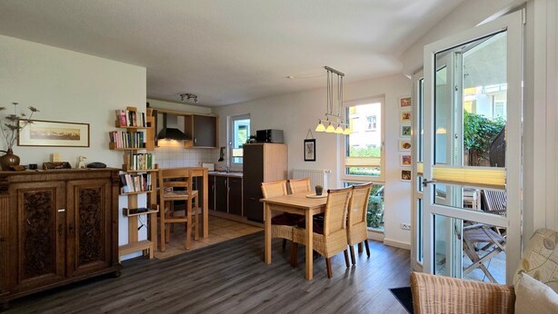 Une cuisine spacieuse avec un coin repas, des meubles en bois et une grande fenêtre offrant une vue sur l’extérieur.