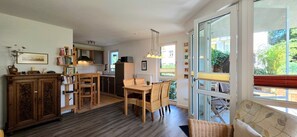 Eine geräumige Küche mit Essbereich, Holzmöbeln und einem großen Fenster mit Blick ins Freie.