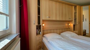 Une chambre à coucher avec un lit, une armoire et une fenêtre.