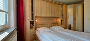 A bedroom with a bed, a wardrobe, and a window. - Vacation Rental i38 - Ground-floor 2-room apartment near the beach, Wi-Fi (Graal-Müritz)
