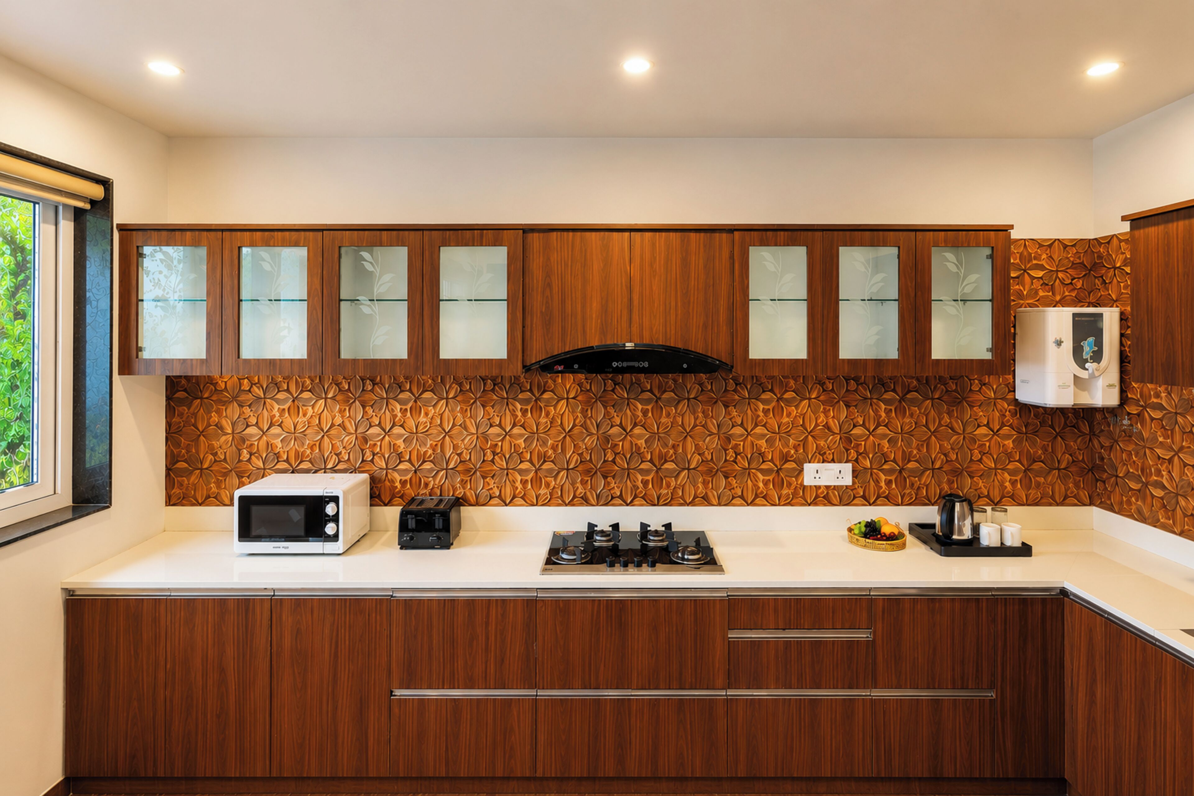 Una cucina moderna con mobili in legno, un forno a microonde, un tostapane e un dispenser d'acqua.