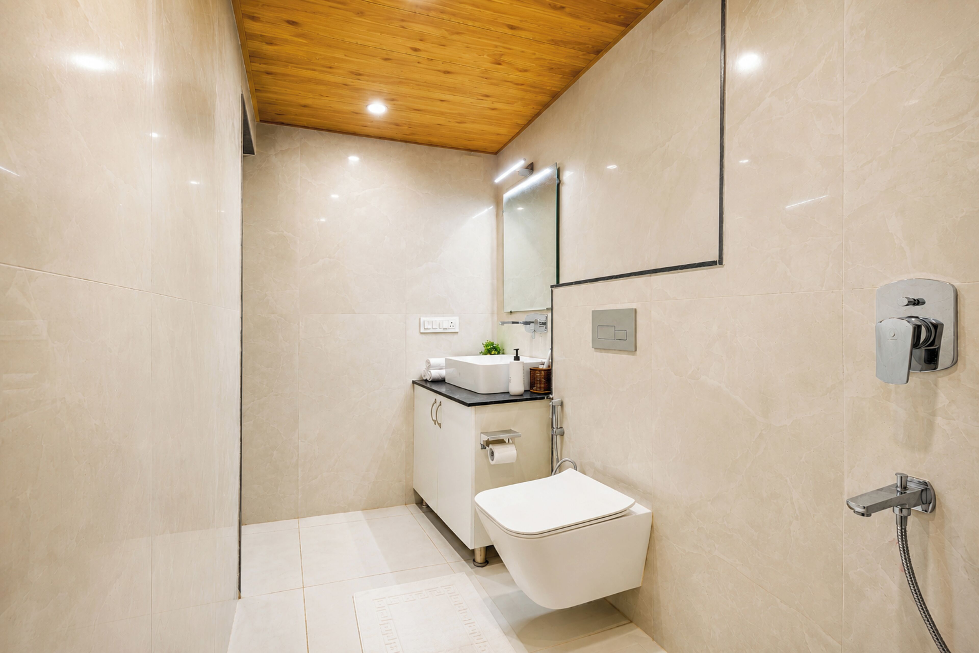 Ein modernes Badezimmer mit Holzboden, Toilette, Waschbecken und Dusche.