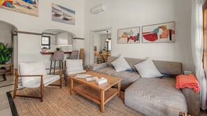 Un salon comprenant un canapé, des fauteuils, une table basse et des œuvres d’art accrochées aux murs.