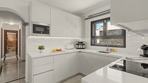 Une cuisine moderne avec des meubles blancs, un four à micro-ondes encastré, un grille-pain et une fenêtre donnant sur un beau paysage.